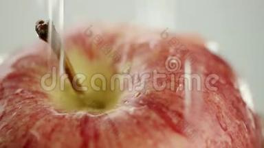 在视频中，我们看到一个红色的苹果，水从顶部像水滴一样倾泻，白色的背景，特写